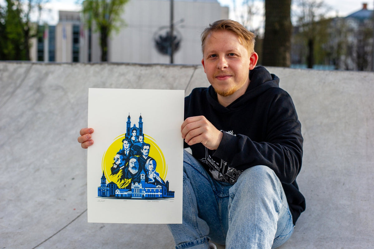 A man wearing a black hoodie and blue jeans sits on concrete at an outdoor skatepark, holding up a white art print featuring a blue graphic illustration of a castle and faces on a yellow background.